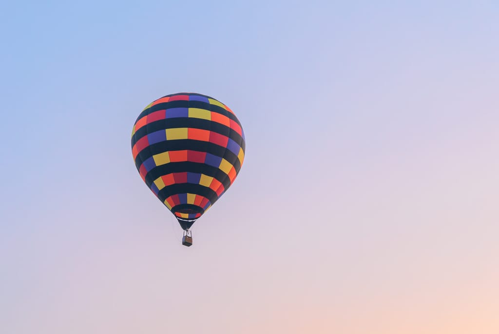 Hot air balloon flying on sky at sunset