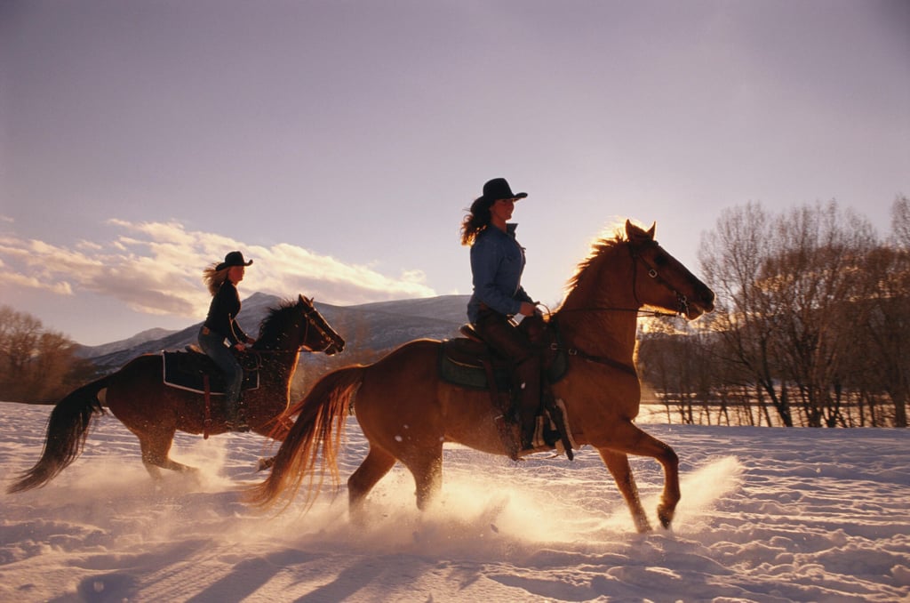 Two young women horseback riding, winter, side view