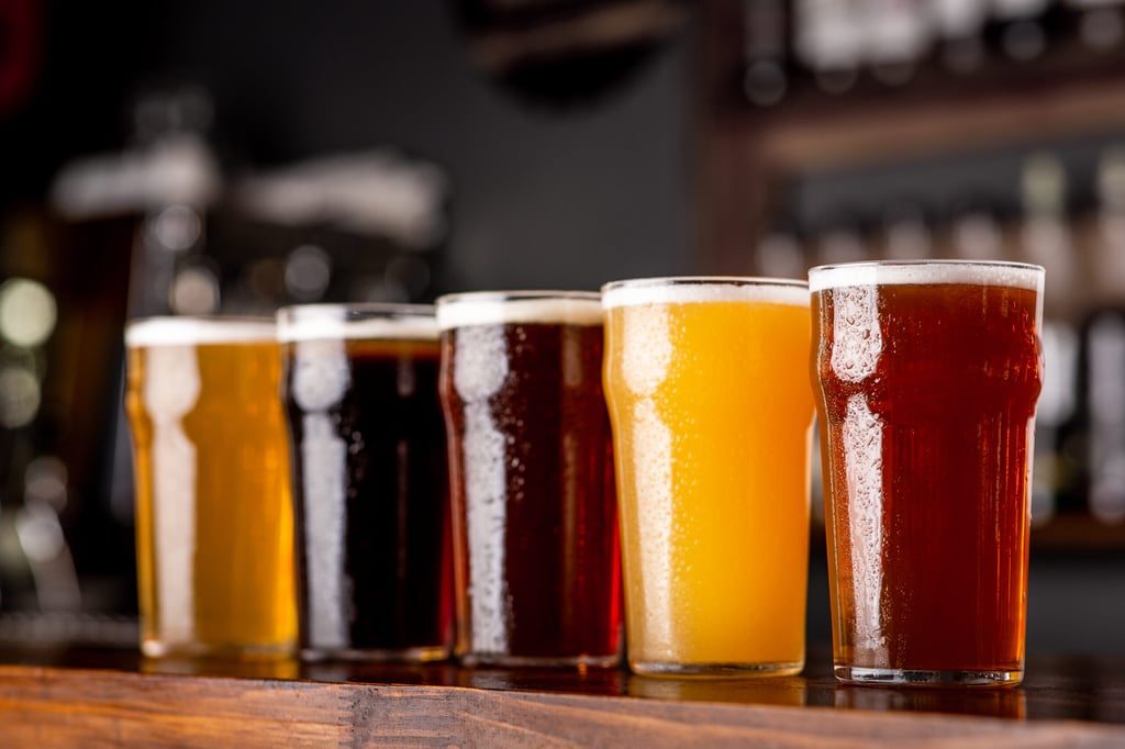 Craft beer and industry. Lager, ale and light, dark, unfiltered beer in glasses on wooden bar counter in pub interior, close up, indoor