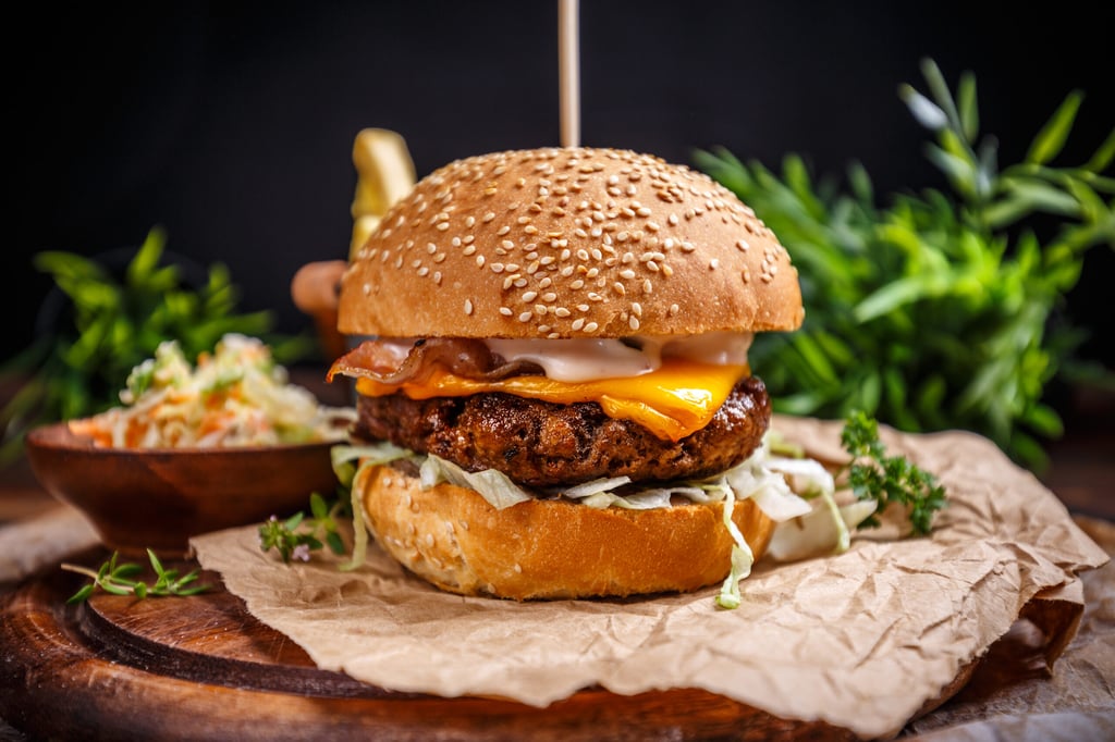 Tasty grilled beef burger with cheese and cabbage served on pieces of brown paper