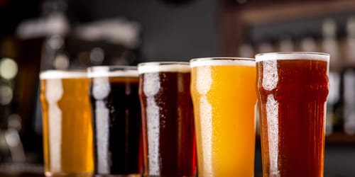 Craft beer and industry. Lager, ale and light, dark, unfiltered beer in glasses on wooden bar counter in pub interior, close up, indoor