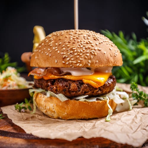 Tasty grilled beef burger with cheese and cabbage served on pieces of brown paper