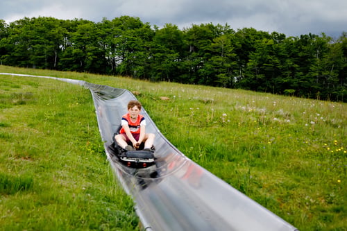 Young boy riding down an alpine slide on a toboggan